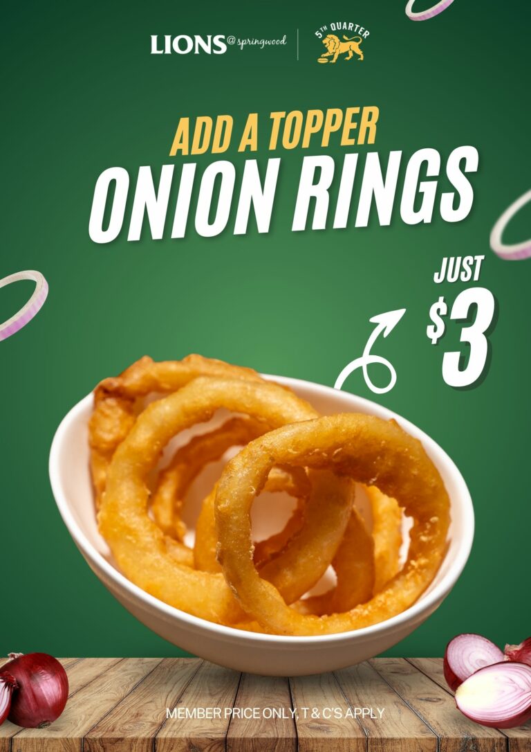 Golden, crispy onion rings served in a white bowl on a wooden surface with onions in the background – available as a $3 add-on at Lions@Springwood. Let me know if you'd like any refinements! 😊